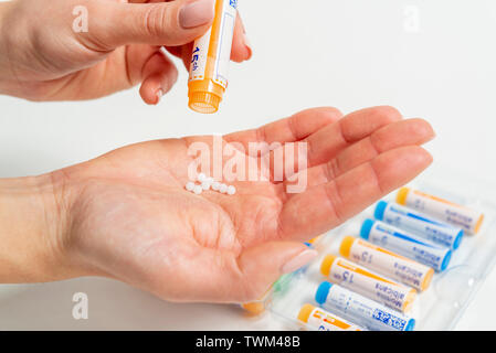 Homeopathic tubes: homeopathic granules, tubes from the Boiron laboratories. Woman putting homeopathic granules in her hand Stock Photo