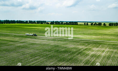tractor rides on the field and carries bales of hay aerial view Stock Photo