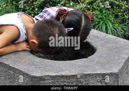 Children gaze into a well in a park in Suzhou China Stock Photo