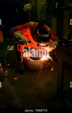 welder and his helper fabricate pipe in a workshop wearing with ...