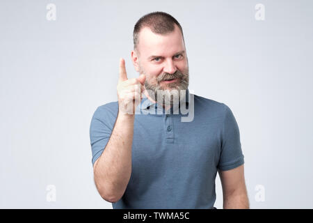 Satisfied mature man in blue clothes showing index finger up Stock Photo