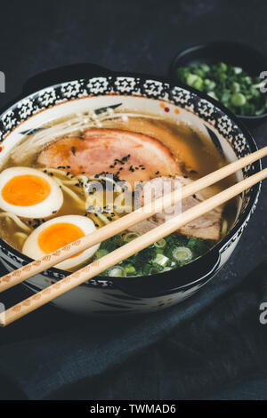 Ramen Soup with Udon Noodles, Pork and Eggs on Dark Background Stock Photo