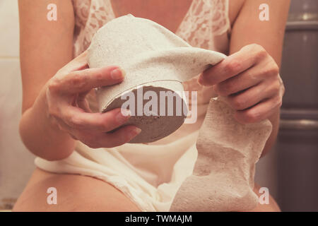 A woman sitting on the toilet with toilet paper coping with their natural needs. Stock Photo