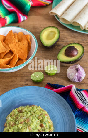 Mexican guacamole with ingredients close-up on the table Stock Photo