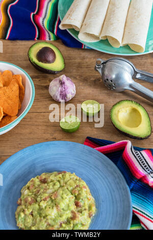 Mexican guacamole with ingredients close-up on the table Stock Photo