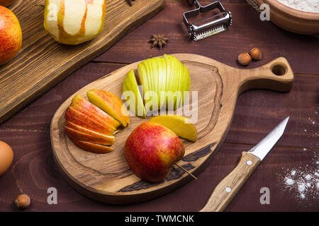 Sliced apples on a wooden board among the products for making apple pie or other baking. Autumn food concept Stock Photo