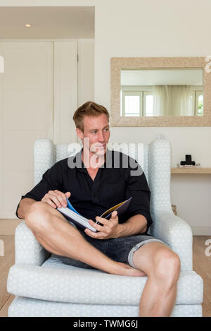 Caucasian man sitting on a sofa with a book Stock Photo