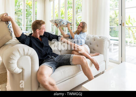 Couple having a pillow fight on the couch Stock Photo