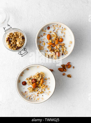 Granola breakfast with fruits, nuts, milk and peanut butter in bowl on a white background. Healthy breakfast cereal top view Stock Photo