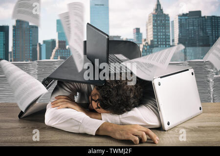 Tired businessman sleeping under a pile of laptops due to workload Stock Photo
