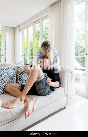 Couple relaxing together on sofa with laptop computer in luxury villa Stock Photo