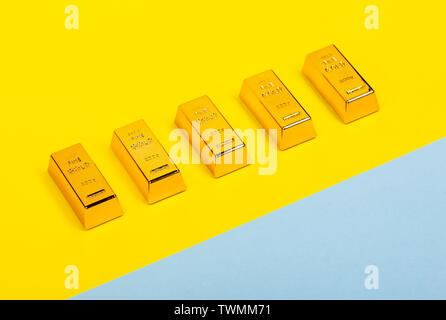 Bars of gold bullion on yellow and light blue background. Financial concept. Stock Photo