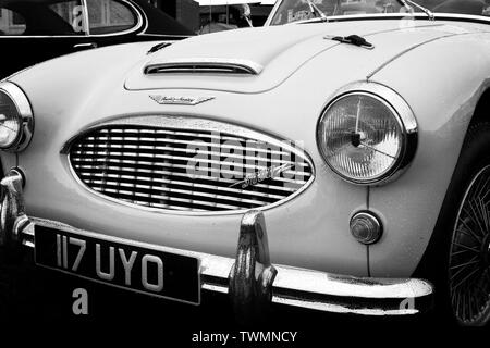 Black and white front view image of a classic Austin Healey 3000 sports car showing bonnet, grille, headlights and decals. Stock Photo