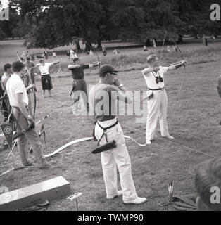 1960s, historical, archery competition, male and female archers on a line taking aim with bows and arrows, England, UK. Stock Photo