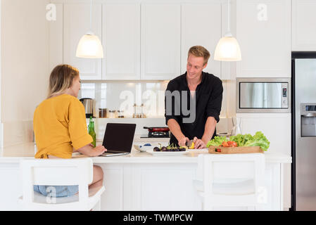 Couple making lunch on a white island kitchen at home Stock Photo