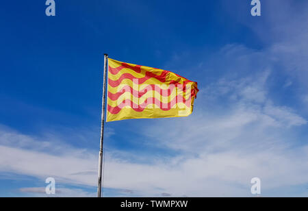 The developing Catalan flag on the background of the blue cloudy sky. Stock Photo