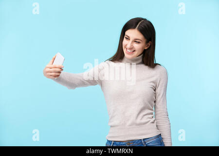 beautiful young caucasian woman taking a selfie, happy and smiling, isolated on blue background Stock Photo