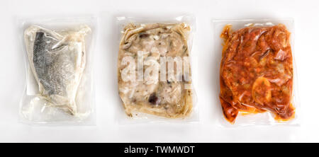 Three different fresh vacuum packed healthy meals in plastic air-tight wrapping with a fish fillet, rabbit and ossobucco arranged on a white backgroun Stock Photo