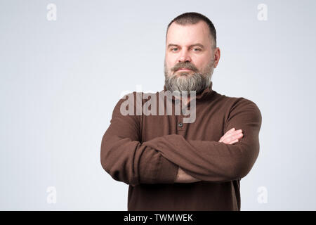 Serious mature european man standing with arms folded Stock Photo