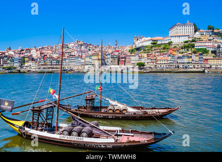 Typical portuguese wooden boats, called 'barcos rabelos' transporting wine barrels on the river Douro with view on Villa Nova de Gaia in Porto, Portug Stock Photo