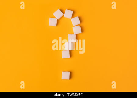 white sugar cubes shaped as a question mark on orange background. Top view. Diet unhealty sweet addiction concept Stock Photo