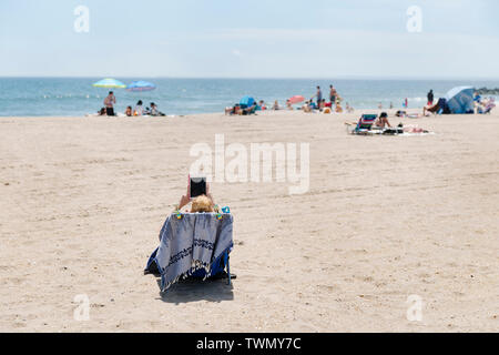 A woman reading on the beach at The Rockaways. Stock Photo