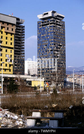 15th March 1993 During the Siege of Sarajevo: the badly damaged twin Unis Towers standing next to the Holiday Inn Hotel on Sniper Alley. The white building between the towers is the Dr Abdulah Nakas General Hospital, known locally as the 'City' or 'French' Hospital during the war. The besieging Bosnian Serb forces were barely 200 metres away. Stock Photo