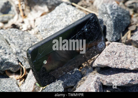 Broken cellphone abandoned and lost among the gravel. Stock Photo