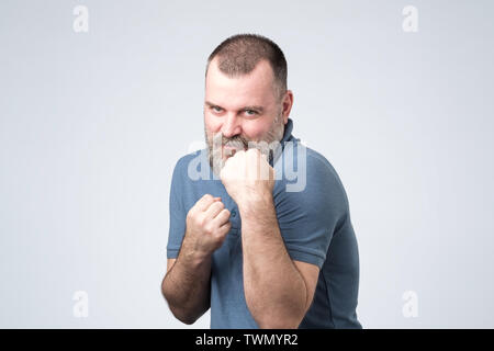 man in blue shirt standing in boxer pose with raised fist Stock Photo