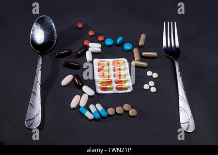 Isolated shot of place setting with nutritional supplement and pharmacy drugs on black background Stock Photo