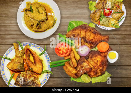 Indian fish food (cuisine) dishes on display comprising of deep fried pomfret fish with rohu fish and hilsa fish curry Stock Photo