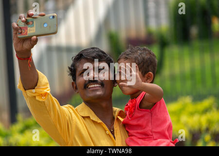Bangalore, Karnataka India-June 04 2019 : Father and little cute daughter taking picture or selfie with Mobile Phone or cellphone camera at tourist pl Stock Photo