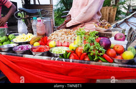 indian street food vendor selling spicy chickpea bengal gram chole mixture garnished with freshly cut onion,cucumber chilli and tomato Stock Photo