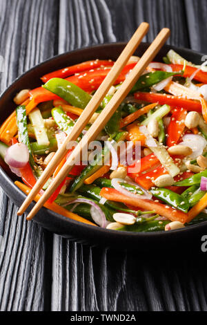 Chinese fresh vegetable salad with sesame and peanuts close-up on a plate on the table. vertical Stock Photo