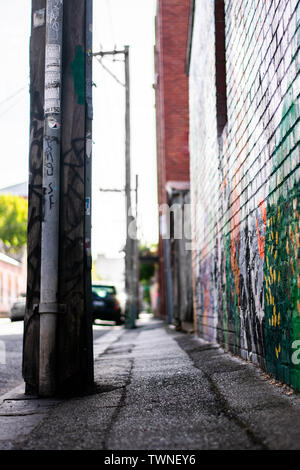 Graffiti on brick wall on urban sidewalk with telephone pole Stock Photo