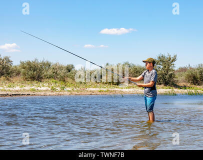 Sulina, Romania - A boy fishing in the Danube river near Sulina, Romania, on a sunny day Stock Photo