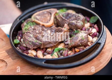 Serving grilled beef steak with beans close-up on a plate on a table. Restaurant concept Stock Photo