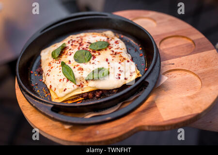 closed mini-quiche quiche stuffed with meat. Argentinian dish of tortillas, cheese, basil and meat on black pan Stock Photo