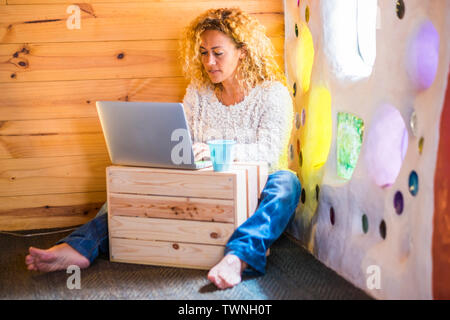 People at wotk in alternativ ehome office workstation - curly blonde pretty woman with technology computer laptop and internet connection working on t Stock Photo