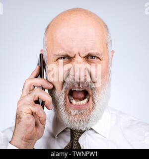 Angry furious mid age businessman having a phone call with his smartphone Stock Photo