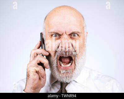 Angry furious mid age businessman having a phone call with his smartphone Stock Photo
