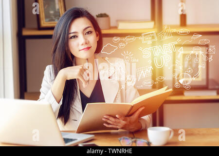 portrait of beautiful and confident Asian business woman in working with notebook laptop and book manage job work at workplace with startup business Stock Photo