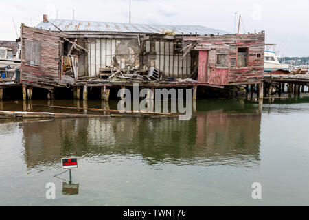 Derelict buildings on a pier in South Portland, Maine, Usa. A No Tresspassing marker is in the water to keep people away from these unsafe structures. Stock Photo