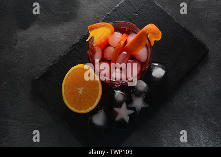 Negroni cocktail. Smoky Italian aperitif with gin, campari, martini Rosso, orange and ice cubes served in glass on dark stone background Stock Photo