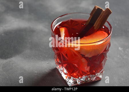 Negroni cocktail. Smoky Italian aperitif with gin, campari, martini Rosso, orange and ice cubes served in glass on dark stone background Stock Photo