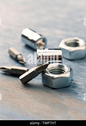 Bits for a screwdriver and hex nuts on wooden background. Close up. Copy space. Stock Photo