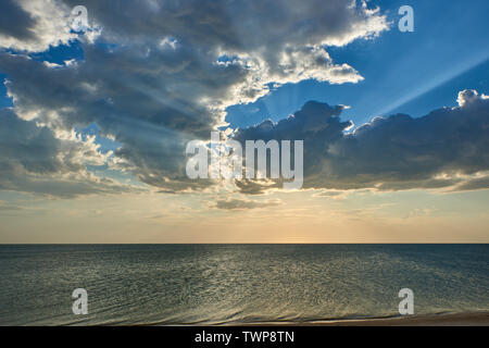 Sunset. Sun rays through the clouds on the sea Stock Photo