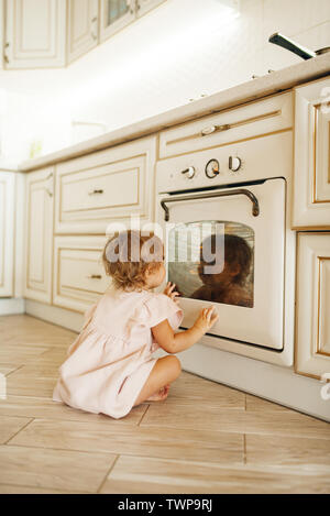 Female kid sitting on the floor at the baking oven Stock Photo