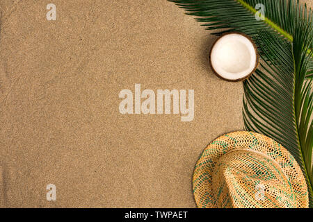 Beach theme on the sand background. Palm leaves, coconut, hat on the sand. Top view. Stock Photo