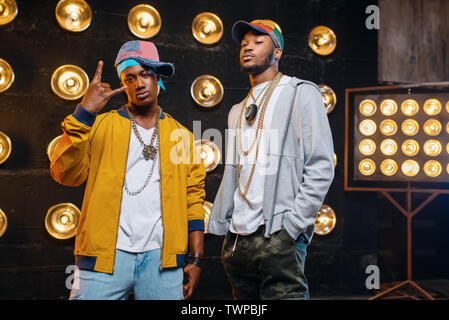 Black rappers in caps on stage with spotlights Stock Photo